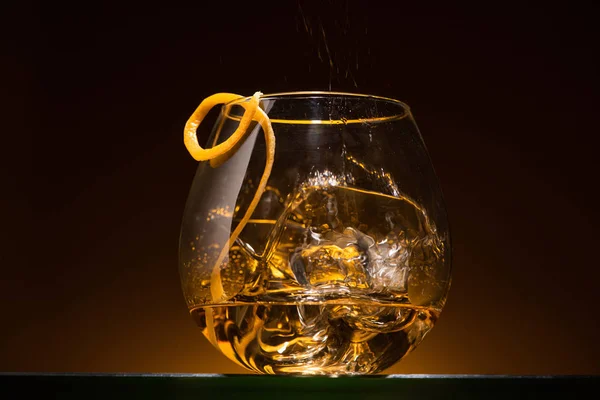 Gjennomsiktig Glass Med Sitrusskall Isbiter Vodka Mørket Med Varmt Baklys – stockfoto