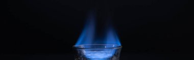 transparent glass with burning liquid isolated on black, panoramic shot clipart