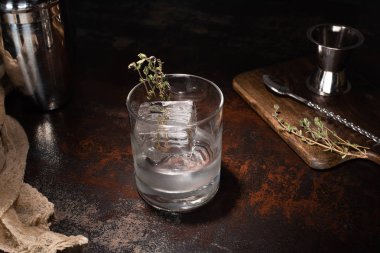 transparent glass with herb, ice cube and vodka on weathered surface clipart