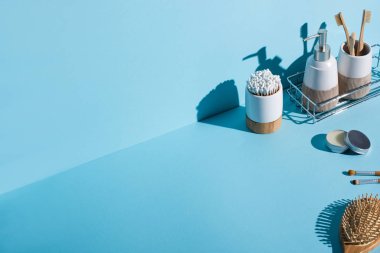 Diş fırçası ve kulak çubuğu olan diş fırçası tutacakları, banyo rafında şeker kutusu, kozmetik fırçalar, mavi arka planda saç fırçası, sıfır atık kavramı.