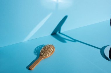 Ahşap saç fırçası ve mavi arka planda gölge, sıfır atık kavramı