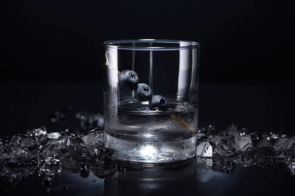 Vidro Transparente Com Vodka Mirtilos Perto Gelo Esmagado Fundo Preto — Fotografia de Stock