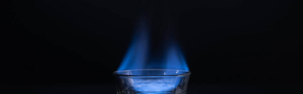transparent glass with burning liquid isolated on black, panoramic shot