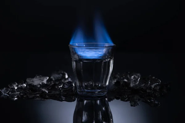 Verre Transparent Avec Liquide Brûlant Près Glace Sur Fond Noir — Photo