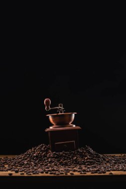 coffee grinder on fresh roasted coffee beans isolated on black clipart