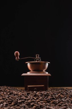 Kahve öğütücüsünün seçici odağı siyah üzerine izole edilmiş taze kavrulmuş kahve çekirdekleri