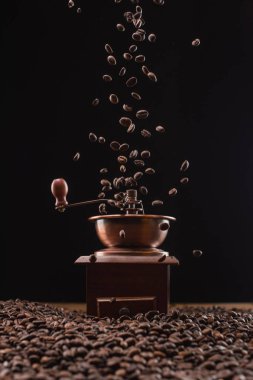 coffee grinder and fresh roasted coffee beans in air isolated on black clipart