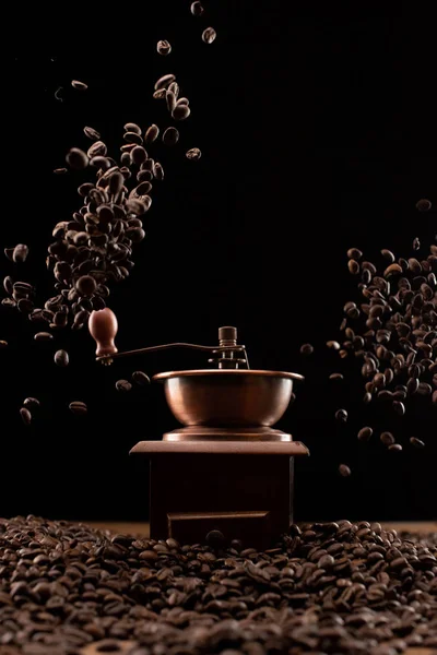 コーヒーグラインダーと黒で隔離された空気中の新鮮な焙煎コーヒー豆 — ストック写真