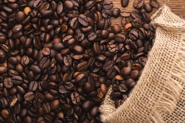 Ovanifrån Färska Rostade Kaffebönor Utspridda Från Säck Träytan — Stockfoto