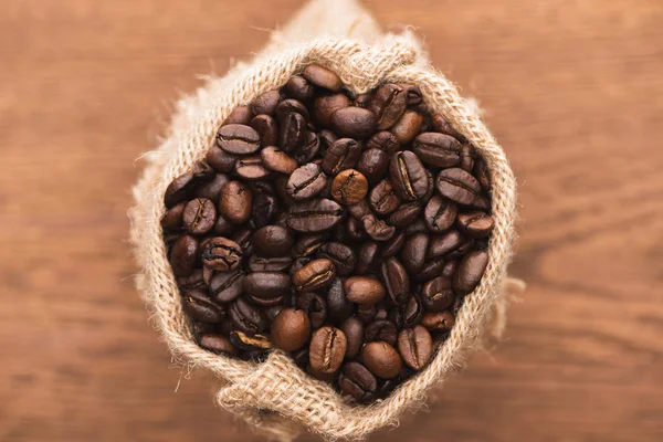 焼きたてのコーヒー豆を木の表面に袋に入れ — ストック写真