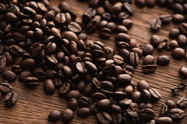 新鮮な焙煎コーヒー豆を木のテーブルの上に散らし — ストック写真