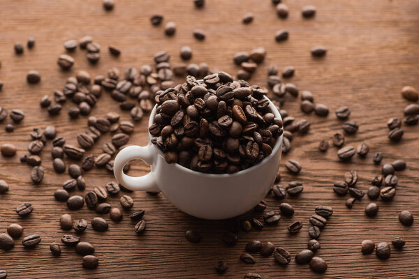 selective focus of cup of fresh roasted coffee beans on wooden table