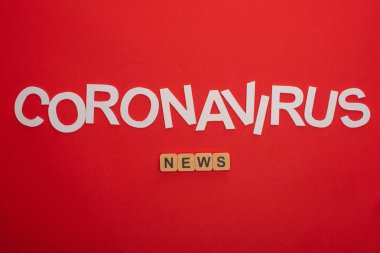 Coronavirus harflerinin en üst görüntüsü ve kırmızı arkaplanda tahta küplerle ilgili haberler.