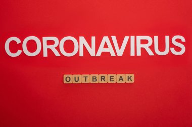 Coronavirüs harflerinin üst görüntüsü ve kırmızı arkaplanda tahta küplerin salgını