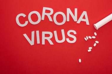 Coronavirus harflerinin üst görüntüsü ve kırmızı arka planda haplar