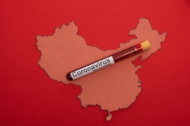 Top view of test tube with blood sample on wooden china map isolated on red clipart