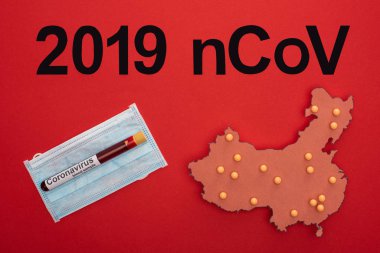 2019 ncov harflerinin üst görünümü, kırmızı yüzey üzerinde tıbbi maske üzerinde test tüpü bulunan porselen haritanın düzeni