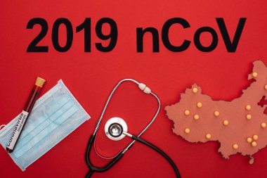 2019 ncov harflerinin üst görünümü, tıbbi maske üzerinde test tüpü ve kırmızı arka planda stetoskop ile porselen haritasının düzeni