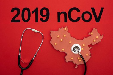 Kırmızı arkaplanda 2019 ncov harfli Çin haritasının düzeninde steteskopun üst görünümü