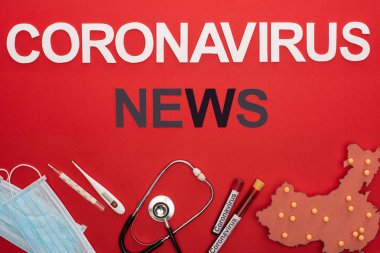 Koronavirüs haberlerinin en üst görüntüsü tıbbi ekipman ve kırmızı yüzeydeki porselen haritası.