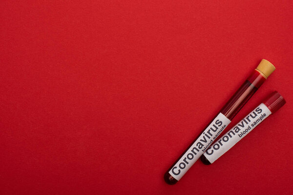 Вид сверху пробирки с образцами крови и утечкой коронавируса на красном фоне
