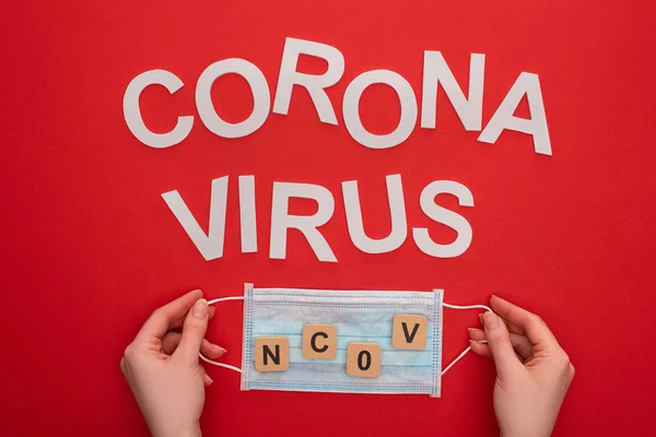 持医用口罩 在木制立方体上有Ncov标志 在红色背景上刻有Coronavirus字样的妇女的头像 — 图库照片
