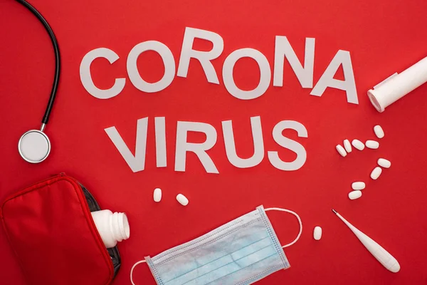 Hapların Üst Görüntüsü Steteskoplu Tıbbi Maske Kırmızı Arkaplanda Koronavirüs Harfleri — Stok fotoğraf