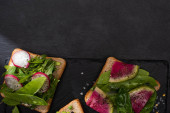 shora pohled na organické toasty se zeleninou na kamenné desce s pepřem a solí