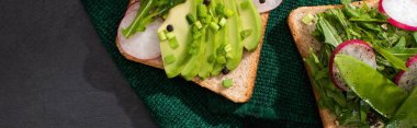 Vejetaryen sandviçleri taze turp ve yeşil kumaş üzerinde avokado ile panoramik çekim
