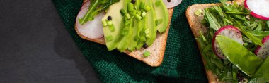 panoramic shot of vegetarian sandwiches with fresh radish and avocado on green cloth clipart