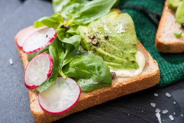 Taze tostları turp, fesleğen ve kumaş üzerine avokado ile kapatın.