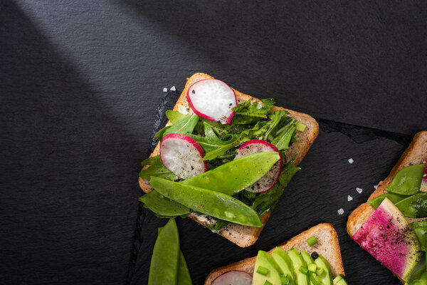 top view of healthy toasts with fresh vegetables with pepper seeds and salt