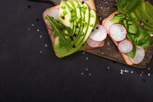 top view of organic sandwiches with vegetables on wooden board 