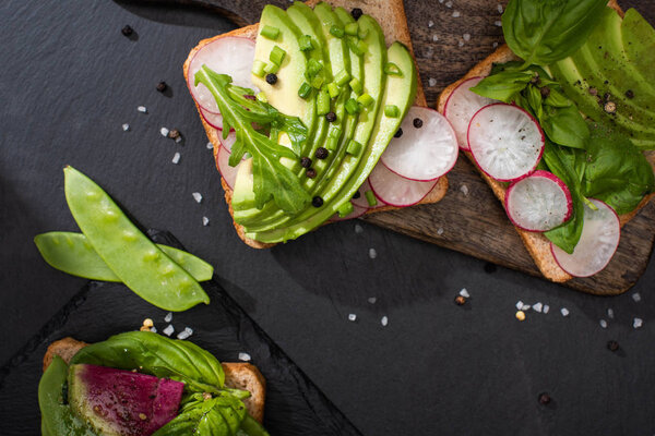 top view of healthy sandwiches with vegetables on stone and wooden boards with pepper and salt