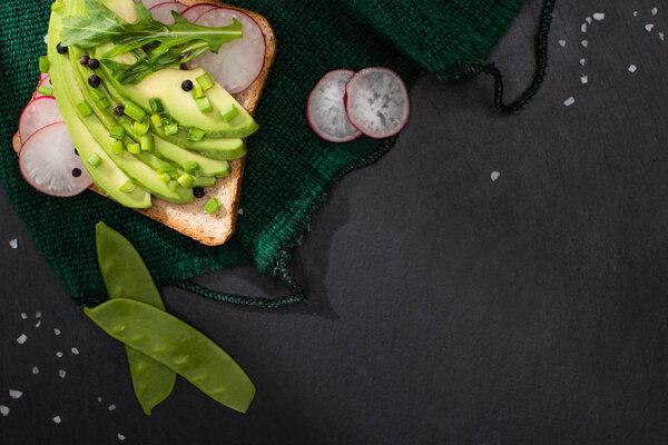 top view of toast with avocado and leek and radish on cloth