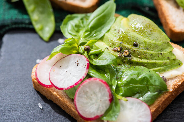 close up of healthy toasts with radish, basil and avocado on cloth