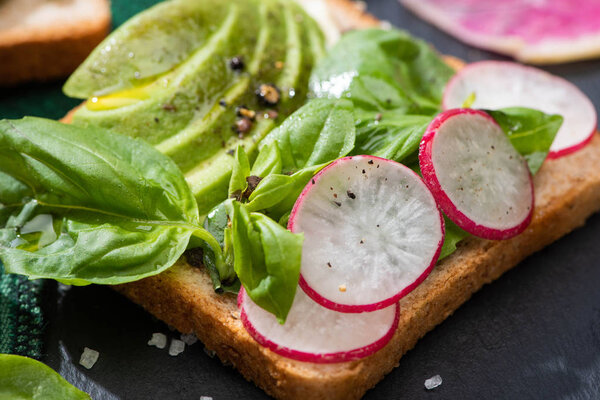 close up of fresh sandwiches with radish, basil and avocado on cloth