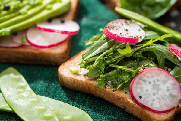 close up of fresh sandwiches with radish and greens on cloth