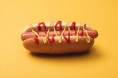 nezdravý hot dog s párkem, hořčicí a kečupem na žluté 