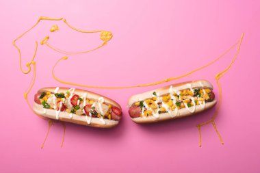 Pembe üzerine iki sosisli, hardallı köpek resmi. 