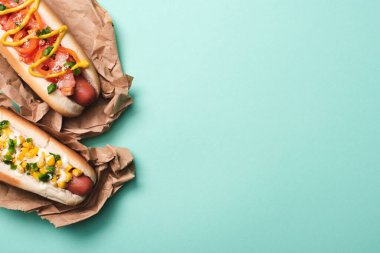 top view of two tasty hot dogs in paper on blue clipart