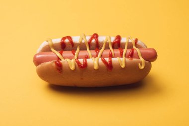 unhealthy hot dog with sausage, mustard and ketchup on yellow  clipart