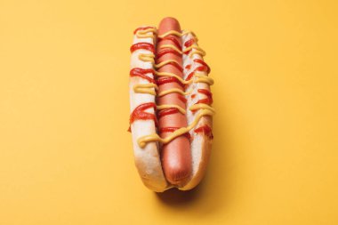 delicious unhealthy hot dog with sausage, mustard and ketchup on yellow  clipart