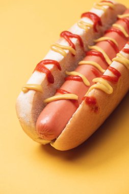 close up of unhealthy hot dog with sausage, mustard and ketchup on yellow clipart