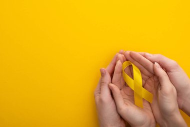 Renkli arka planda sarı kurdele tutan kadın ve erkek manzarası, uluslararası çocukluk kanseri günü konsepti