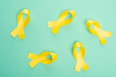 Top view of yellow ribbons on turquoise background, international childhood cancer day concept clipart