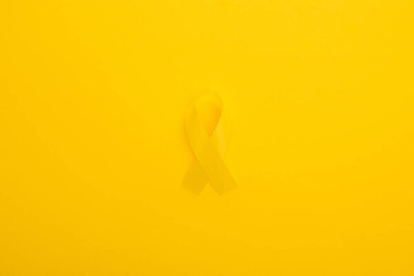 Top view of yellow ribbon on bright colorful background, international childhood cancer day concept