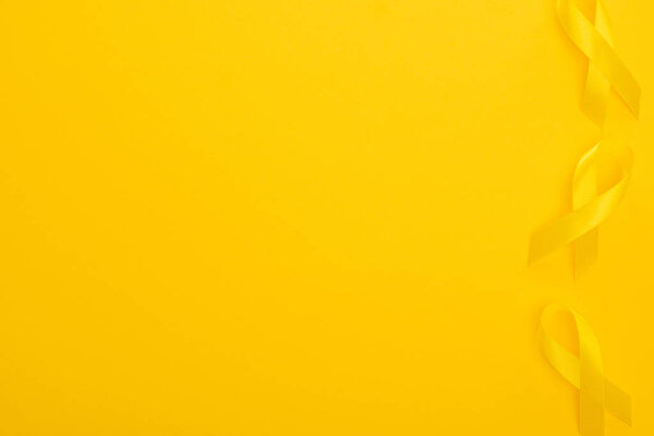 Top view of yellow ribbons on bright colorful background, international childhood cancer day concept
