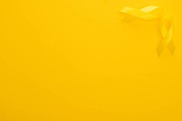 Top view of yellow awareness ribbons on bright colorful background, international childhood cancer day concept 