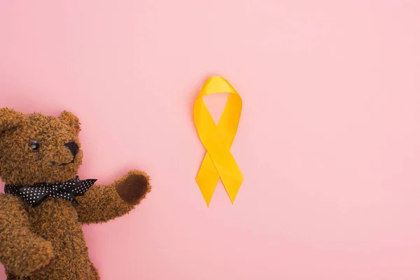 ピンクの背景に黄色のリボンとおもちゃのトップビュー 国際小児がんの日の概念 — ストック写真